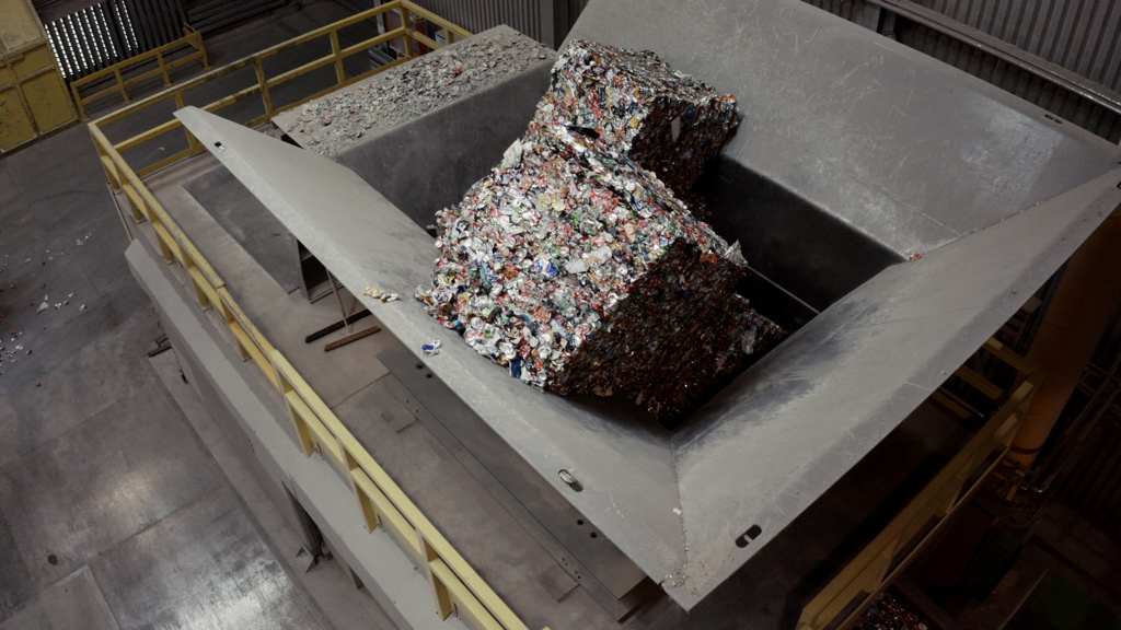 Bales of compressed aluminum cans stacked in a recycling facility.